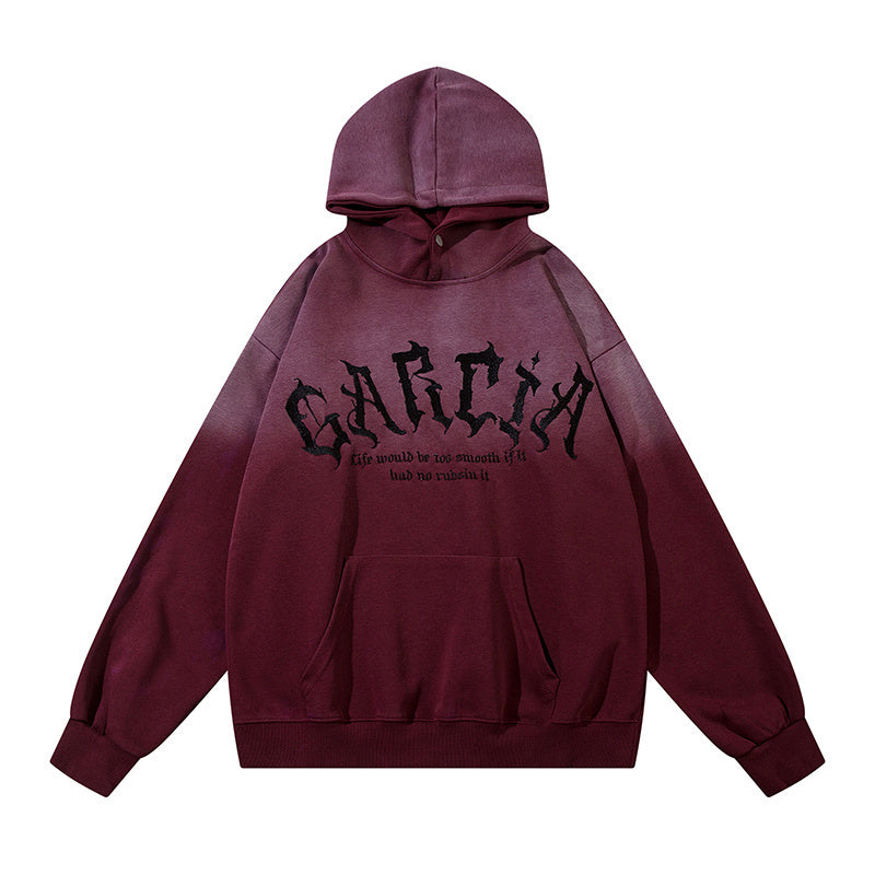 Front view of burgundy and pink gradient hoodie with black embroidered text