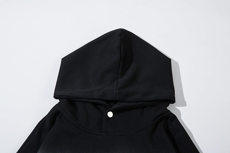 Close-up of hoodie neckline showing snap button detail and premium black cotton-blend fabric texture.