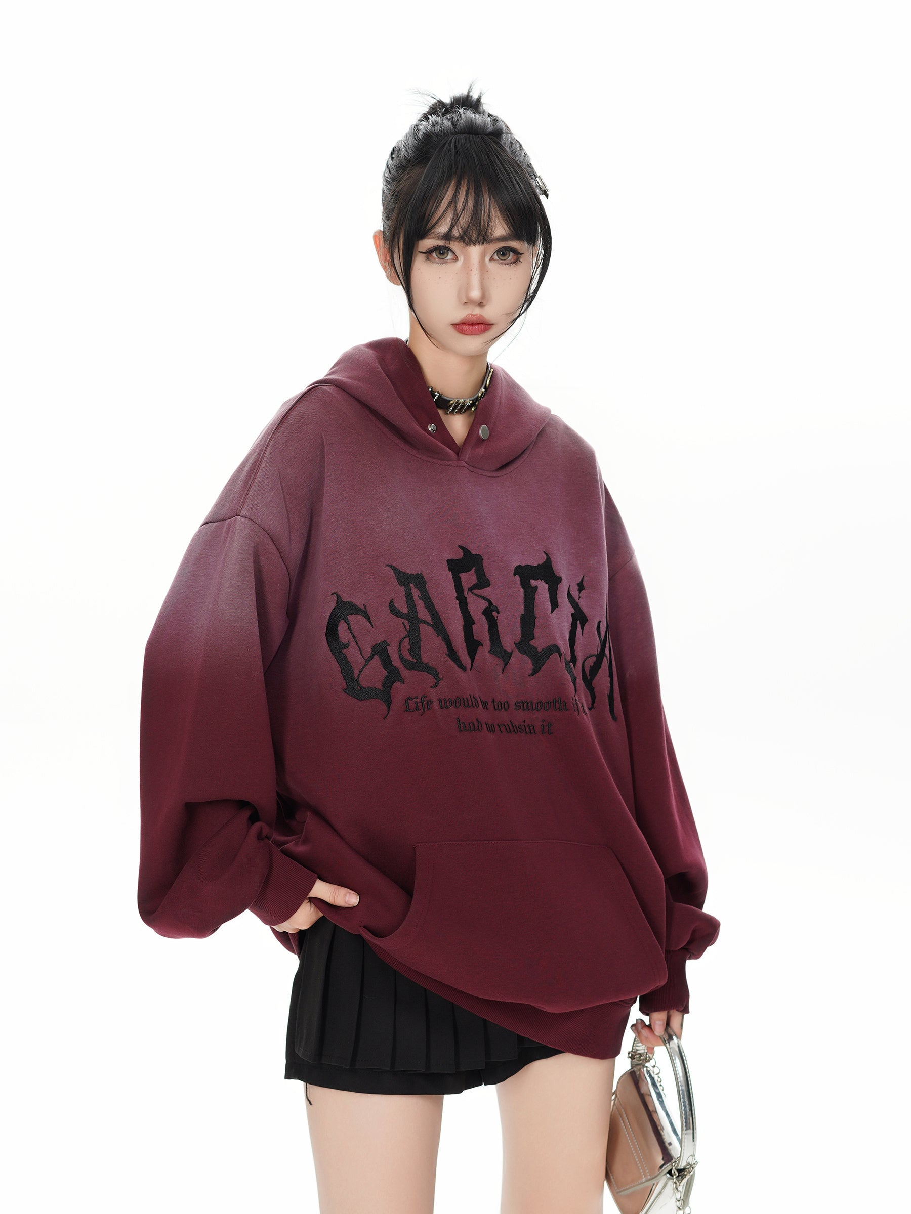 Female model styling the burgundy ombre hoodie with gothic embroidery