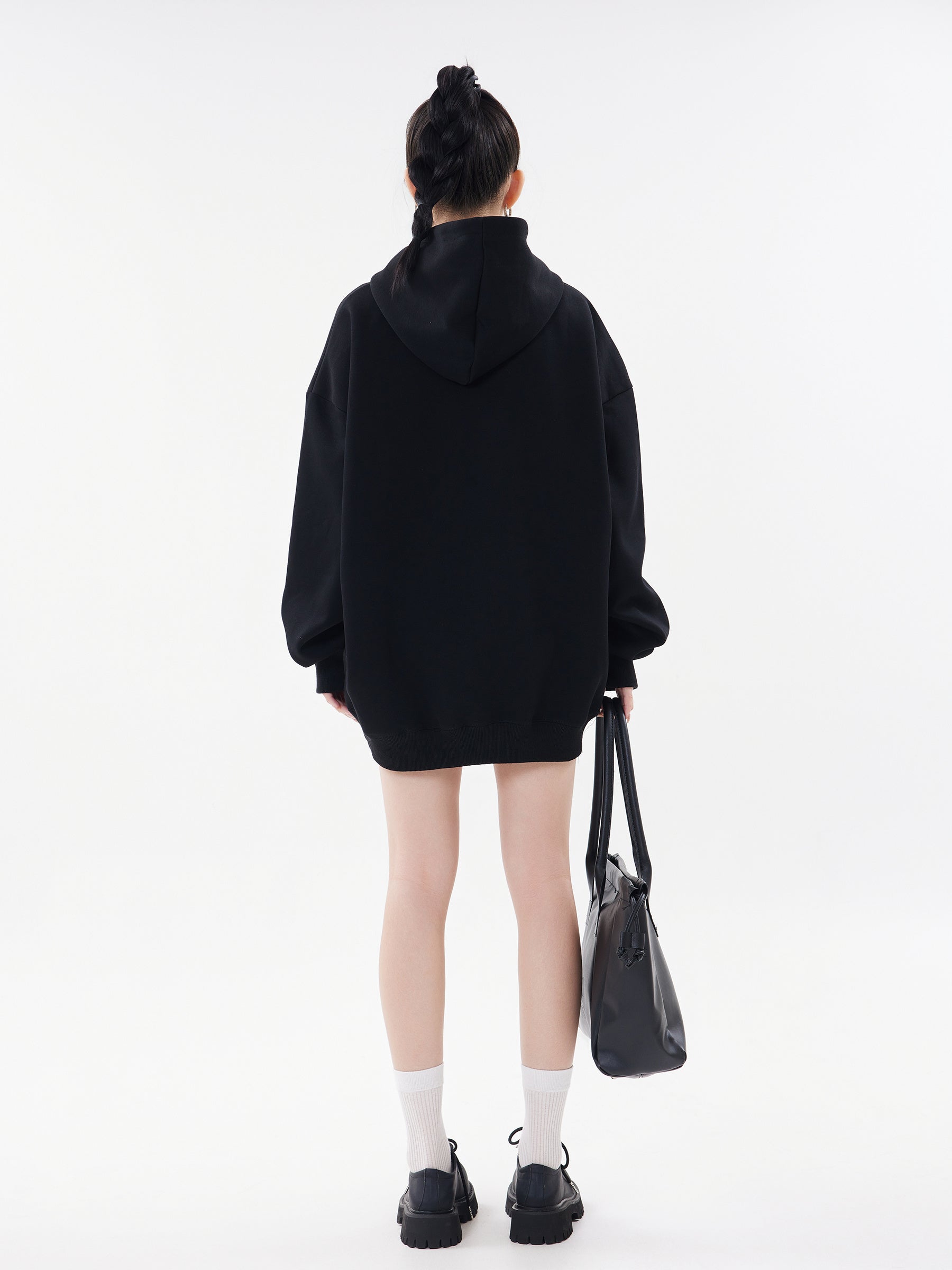 Back view of model wearing black oversized hoodie, showing the relaxed drop-shoulder fit and length.