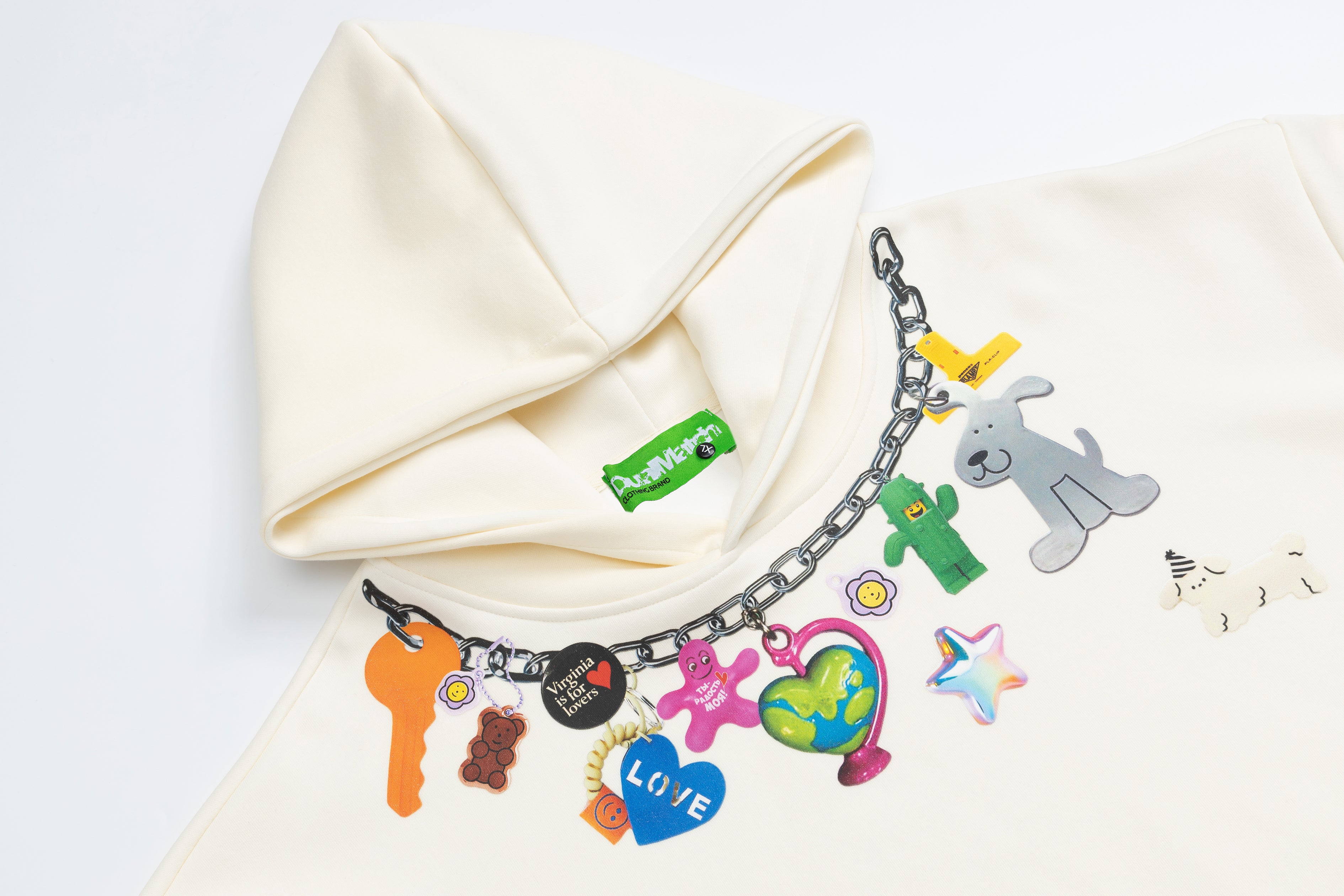 High-angle view of a cream graphic hoodie focusing on the hood and the playful colorful chain print.