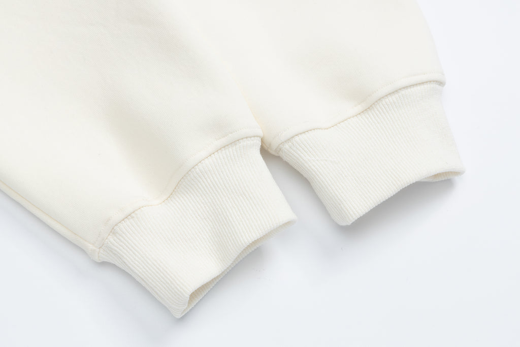 Ribbed sleeve cuff detail on an off-white cotton pullover hoodie, highlighting the high-quality finish.