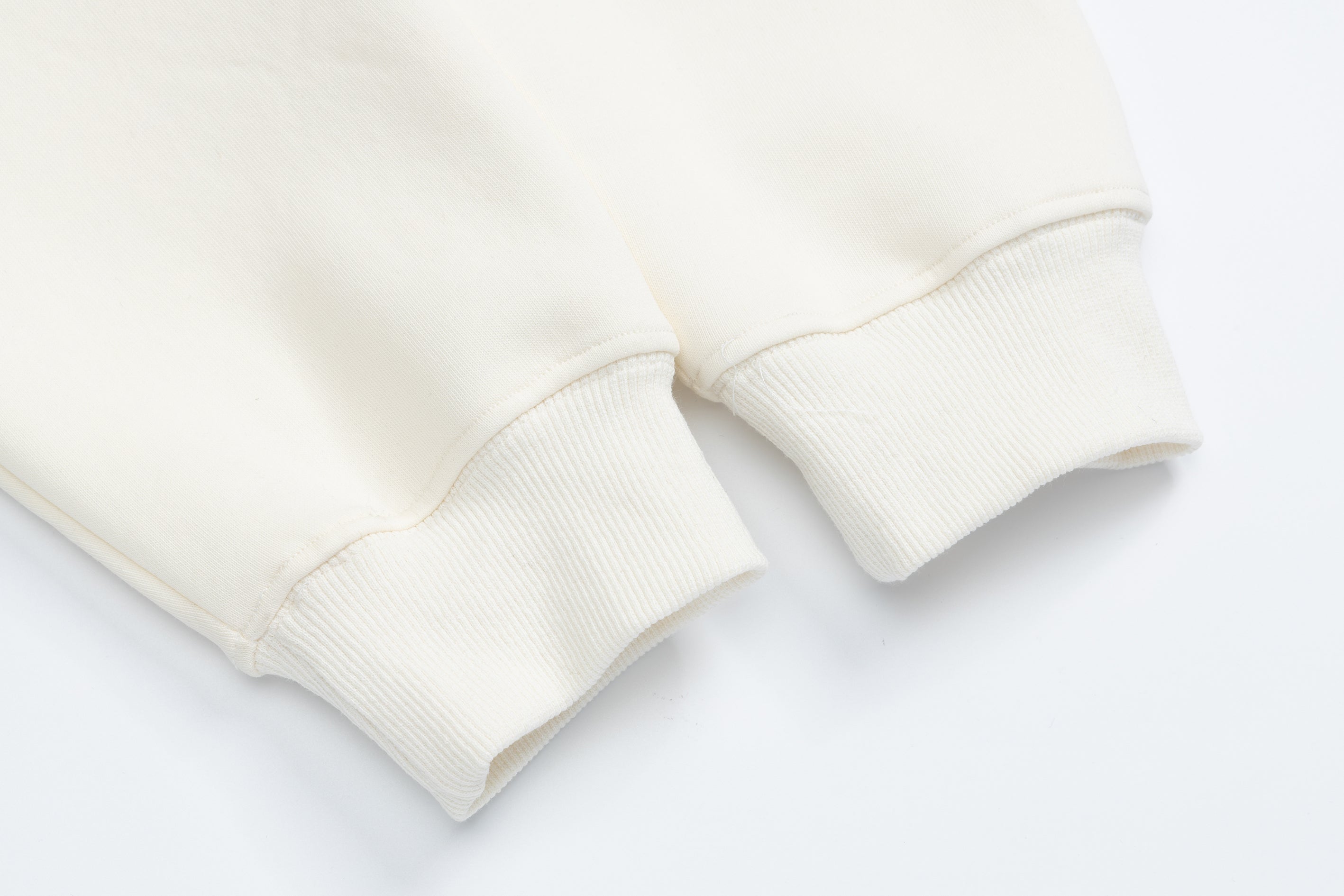 Ribbed sleeve cuff detail on an off-white cotton pullover hoodie, highlighting the high-quality finish.