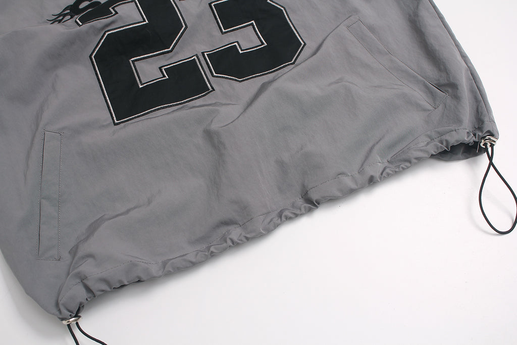 Adjustable elastic hem with cord lock toggle on windbreaker.