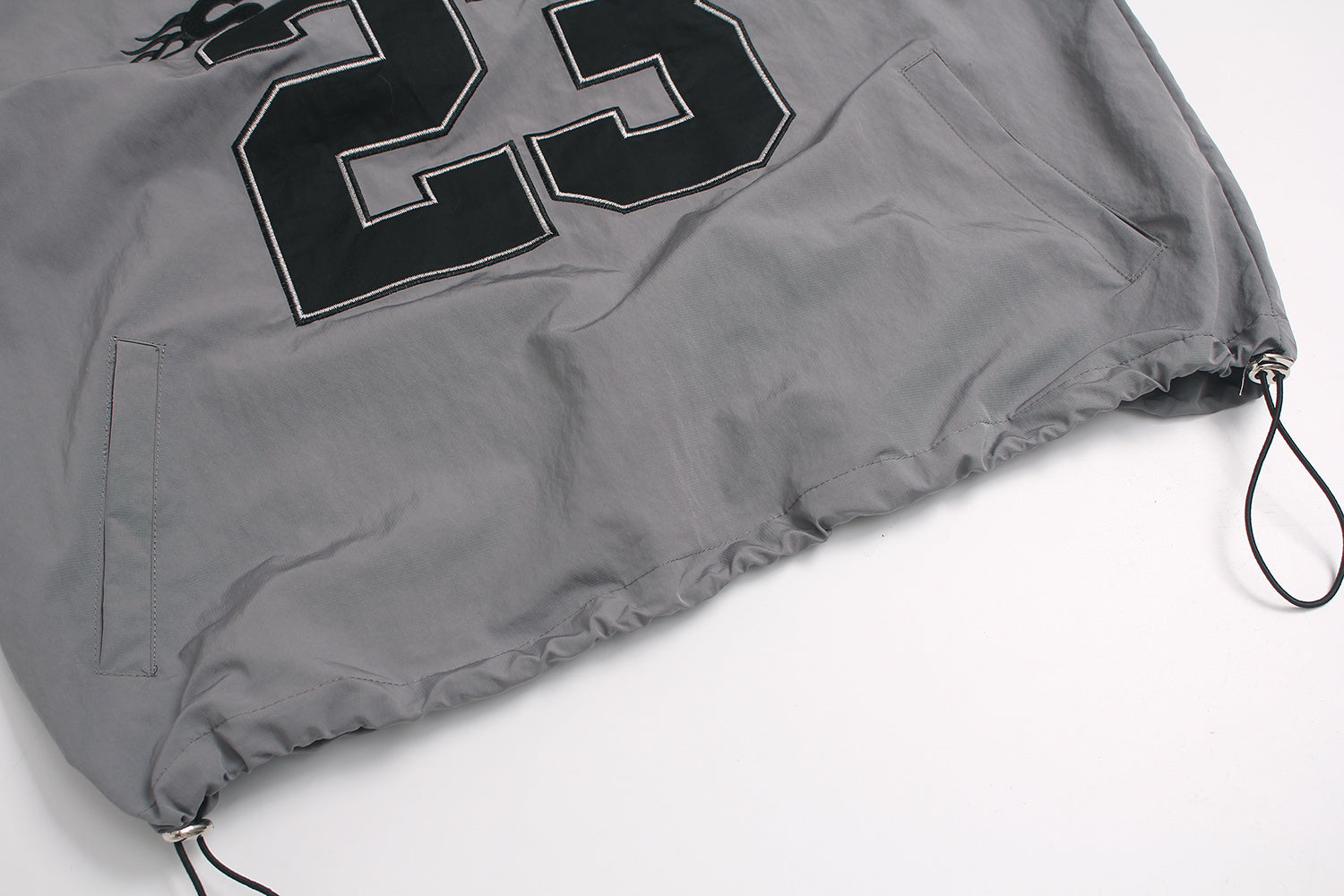 Adjustable elastic hem with cord lock toggle on windbreaker.