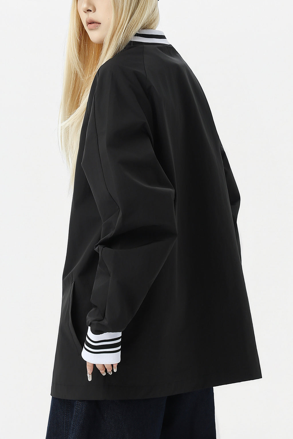 Side view of woman wearing black oversized streetwear windbreaker.