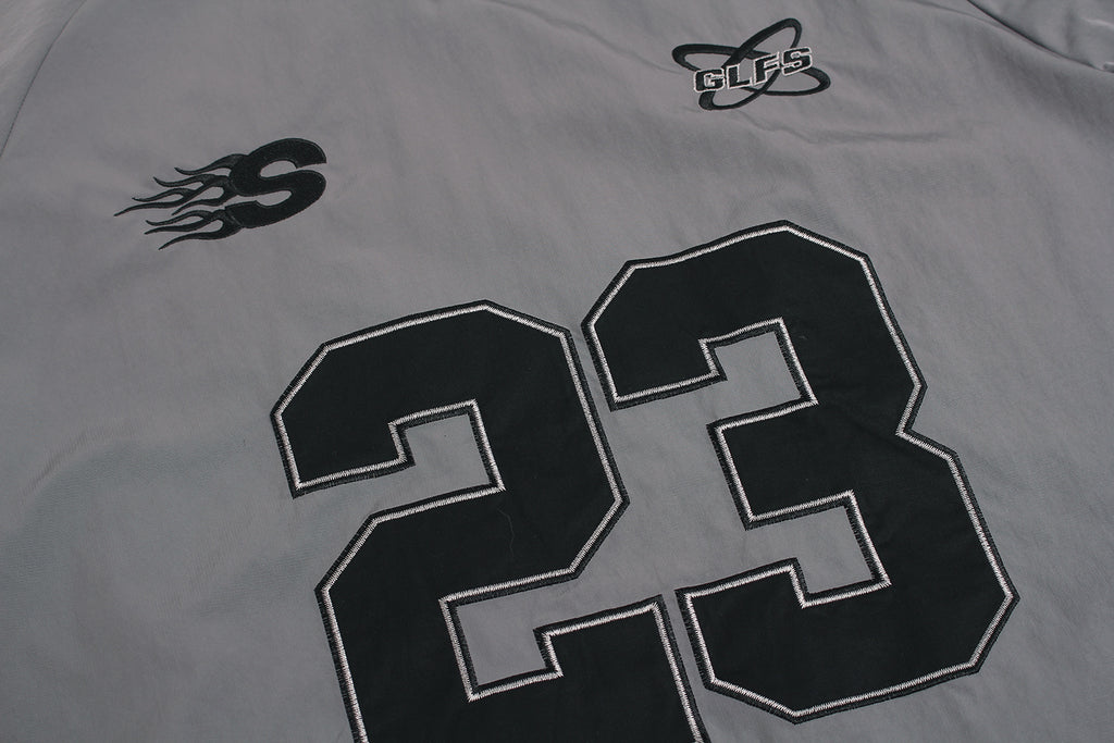 Close up of embroidered GLFS logo on grey waterproof windbreaker.