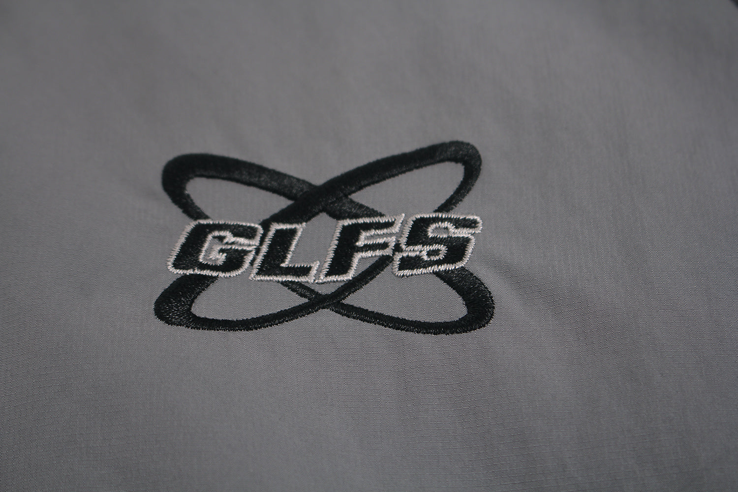 Close up of embroidered GLFS logo on grey waterproof windbreaker.